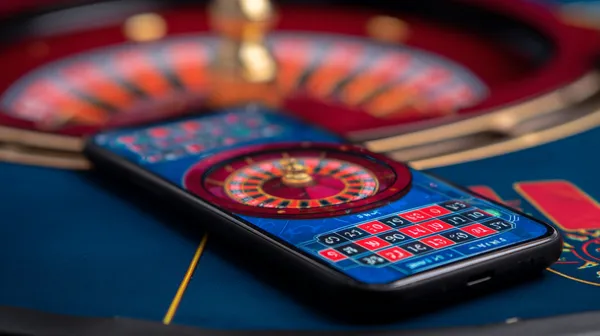 A man celebrating a winning moment on his laptop while gaming symbols float around him, capturing the excitement of JL1 games.